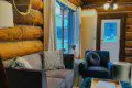 Comfortable sitting area with couch, armchair, and log walls in a Fairbanks Alaska treehouse rental
