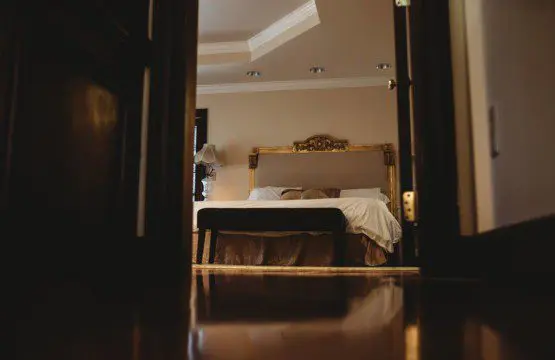 Warm, elegant bedroom with a classic bed frame viewed from doorway in a Fairbanks Alaska adventure lodge