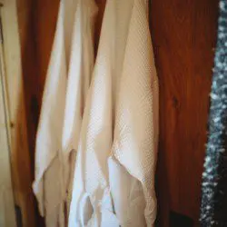 Two soft white robes hanging on wooden wall in a Fairbanks Alaska lodge or treehouse rental