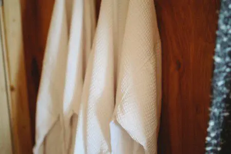 Two soft white robes hanging on wooden wall in a Fairbanks Alaska lodge or treehouse rental
