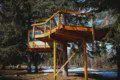 Elevated wooden treehouse cabin with deck nestled in the Fairbanks, Alaska forest