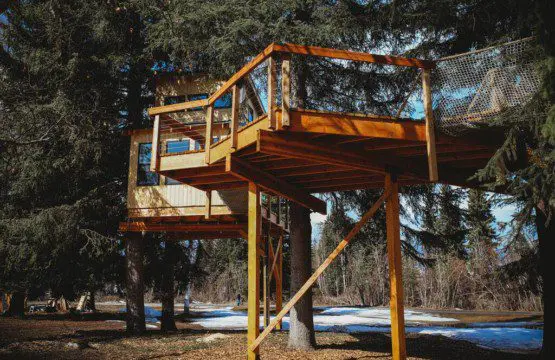 Elevated wooden treehouse cabin with deck nestled in the Fairbanks, Alaska forest