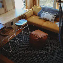 Small sitting area with yellow couch, stools, and pouf in a sunlit Fairbanks Alaska treehouse