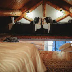 Wood-beamed loft with twin beds and cozy lighting in a Fairbanks Alaska treehouse rental