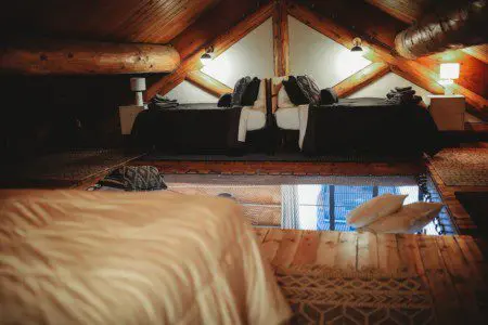 Wood-beamed loft with twin beds and cozy lighting in a Fairbanks Alaska treehouse rental