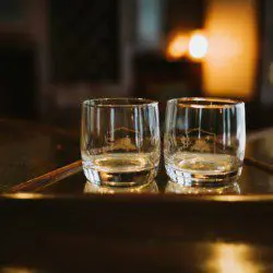 Two empty glasses on a wooden bar counter in a warmly lit Fairbanks Alaska lodge