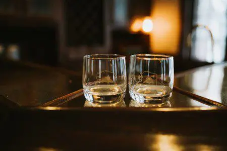 Two empty glasses on a wooden bar counter in a warmly lit Fairbanks Alaska lodge