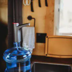 Water jug with dispenser on counter near sink and utensils in a Fairbanks Alaska treehouse