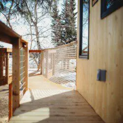 Wooden treehouse cabin with rope bridge entrance nestled in pine forest near Fairbanks, Alaska