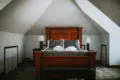 Elegant king-size bed with plush gray and white bedding in an A-frame room with wood furniture