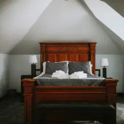 Elegant king-size bed with plush gray and white bedding in an A-frame room with wood furniture