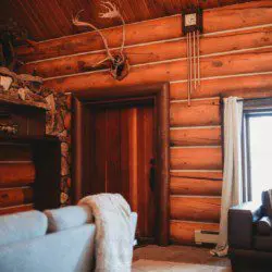 Warm log wall interior with stone fireplace, antlers, and cozy seating in a Fairbanks Alaska lodge