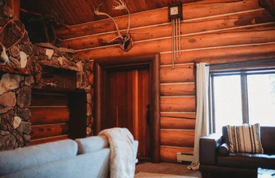 Warm log wall interior with stone fireplace, antlers, and cozy seating in a Fairbanks Alaska lodge