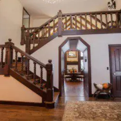 Spacious lodge entry with wooden staircase, decorative railing, and hallway view in Fairbanks Alaska