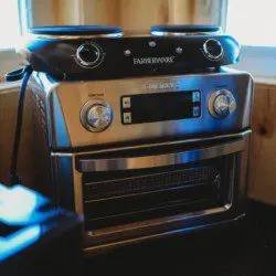 Rustic kitchen with water dispenser, hanging pans, and open shelving in a Fairbanks Alaska treehouse rental