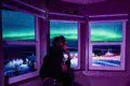 Person watching northern lights through large windows inside a Fairbanks Alaska treehouse rental