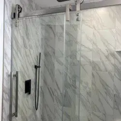 Glass-enclosed shower with marble-style tile in a modern Fairbanks treehouse bathroom