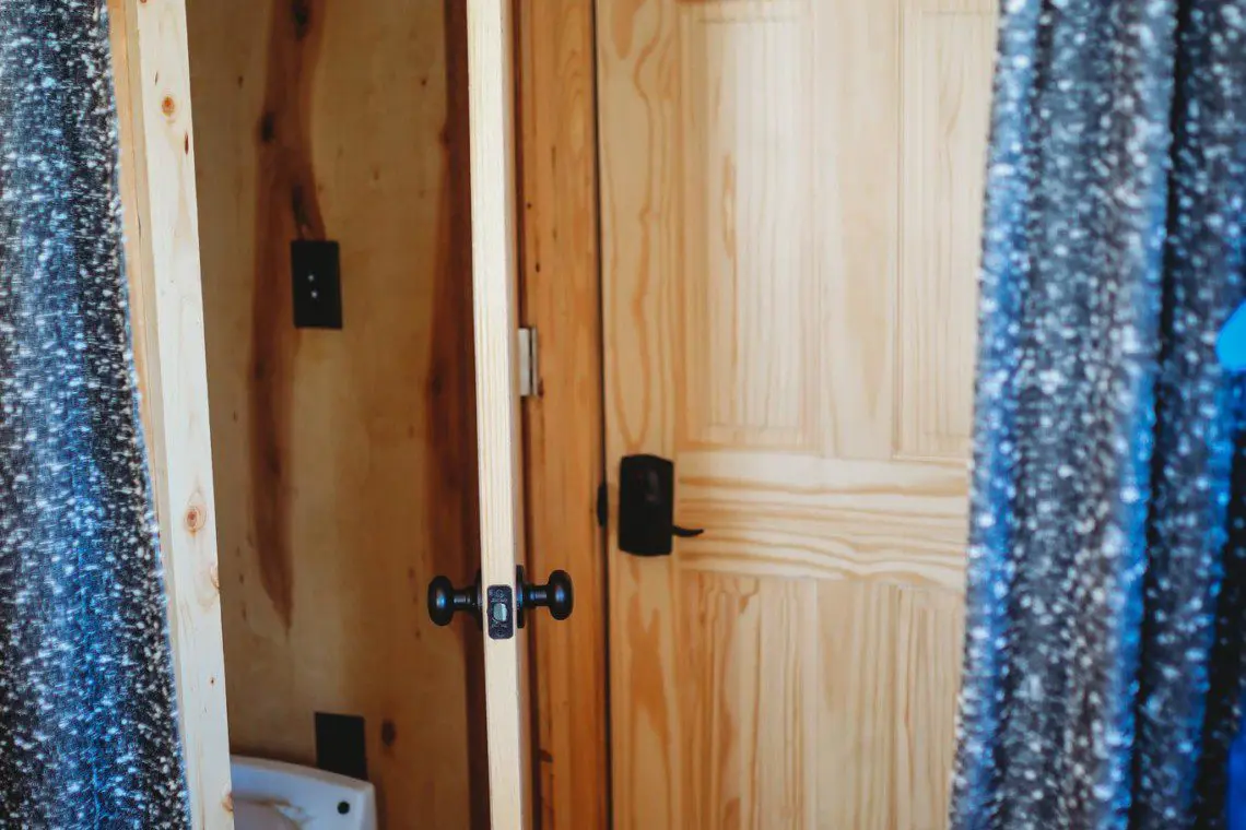 Wood-paneled bathroom with curtain doorway and view of toilet in a cozy Fairbanks Alaska treehouse rental