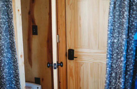 Wood-paneled bathroom with curtain doorway and view of toilet in a cozy Fairbanks Alaska treehouse rental