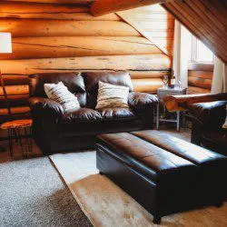 Rustic cabin-style living room with leather furniture in Fairbanks Alaska treehouse rental