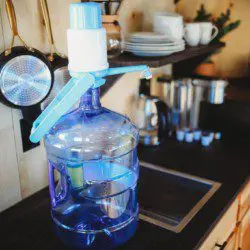Rustic kitchen with water dispenser, hanging pans, and open shelving in a Fairbanks Alaska treehouse rental