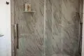 Glass-enclosed shower with marble-style walls in a Fairbanks Alaska treehouse bathroom