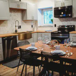 Contemporary kitchen with gold sink, wood counters, and set dining table in a Fairbanks Alaska treehouse