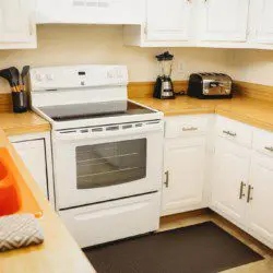 Bright white kitchen with stove, microwave, and countertop appliances in Fairbanks treehouse rental