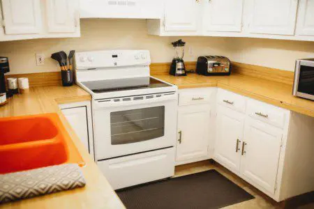 Bright white kitchen with stove, microwave, and countertop appliances in Fairbanks treehouse rental