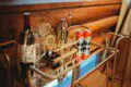 Gold bar cart with wine, glasses, and cocktail tools in a log-walled Fairbanks Alaska treehouse rental