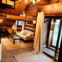 Overhead view of cozy log cabin-style living room with sofa and chairs in Fairbanks Alaska treehouse