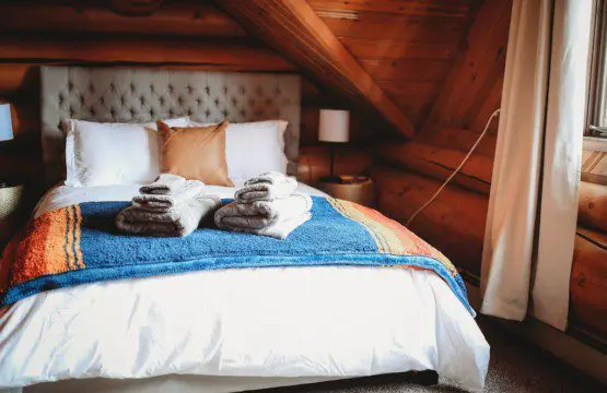 Comfortable bed with colorful blanket and folded towels in a wood-paneled loft in Fairbanks Alaska