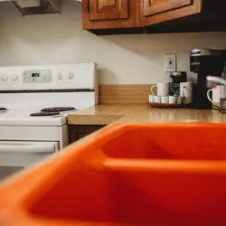 Corner view of treehouse kitchen with stove, orange sink, and beverage station in Fairbanks Alaska