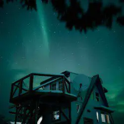  Treehouse-style home under glowing aurora borealis in Fairbanks Alaska night sky