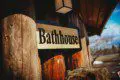 Wooden bathhouse sign mounted on log wall at Fairbanks Alaska lodge with carved bear sculpture