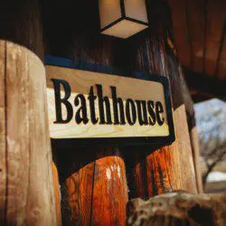 Wooden bathhouse sign mounted on log wall at Fairbanks Alaska lodge with carved bear sculpture