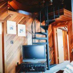 Cozy leather seating and warm wood interior of a Fairbanks treehouse rental with view into a small kitchen