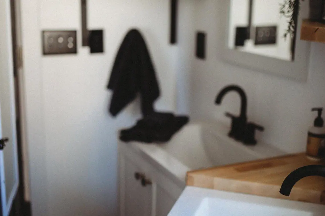 Contemporary bathroom with black fixtures, wood accents, and white sink in a Fairbanks Alaska treehouse rental