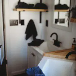 Contemporary bathroom with black fixtures, wood accents, and white sink in a Fairbanks Alaska treehouse rental