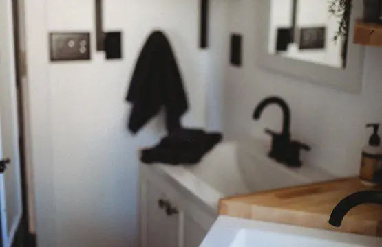 Contemporary bathroom with black fixtures, wood accents, and white sink in a Fairbanks Alaska treehouse rental