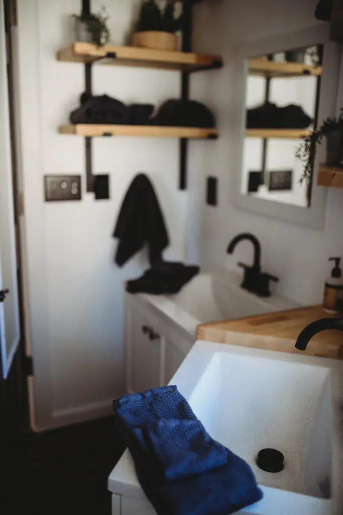 Contemporary bathroom with black fixtures, wood accents, and white sink in a Fairbanks Alaska treehouse rental