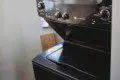 Black stacked washer and dryer in compact laundry nook of Fairbanks treehouse rental
