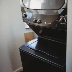 Black stacked washer and dryer in compact laundry nook of Fairbanks treehouse rental