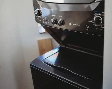 Black stacked washer and dryer in compact laundry nook of Fairbanks treehouse rental