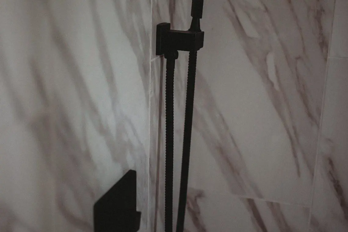 Close-up of a modern black shower fixture against marble tile in a Fairbanks Alaska treehouse rental