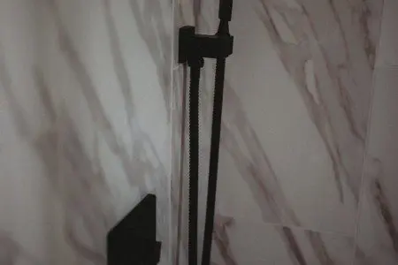Close-up of a modern black shower fixture against marble tile in a Fairbanks Alaska treehouse rental