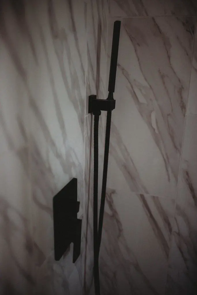 Close-up of a modern black shower fixture against marble tile in a Fairbanks Alaska treehouse rental