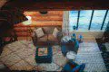 View through mesh of a log cabin-style sitting area with couch, chairs, and large windows in Fairbanks Alaska