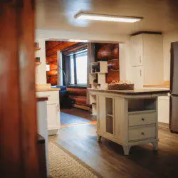 Spacious kitchen with white cabinetry, wood floors, and natural light in a Fairbanks Alaska lodge