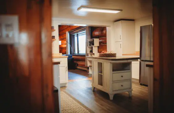 Spacious kitchen with white cabinetry, wood floors, and natural light in a Fairbanks Alaska lodge